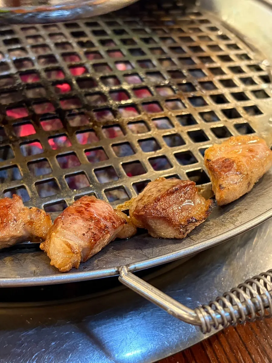 A well-grilled piece of pork neck being picked up