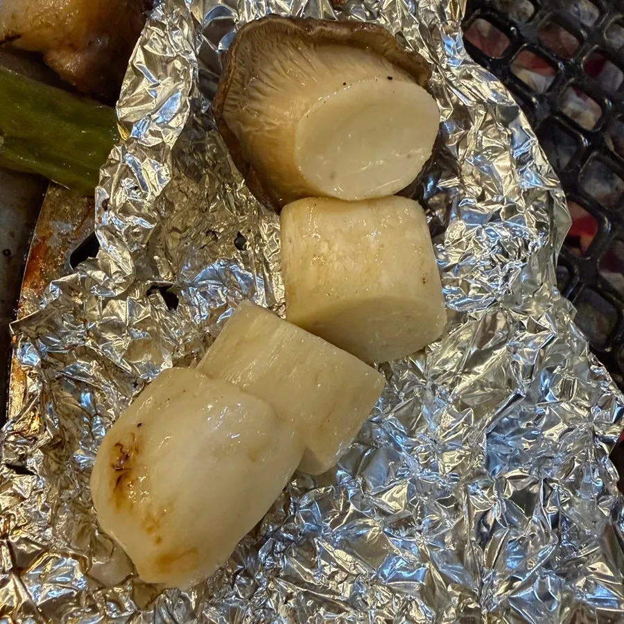 Shishito peppers and foil-grilled king oyster mushrooms at the edge of the brazier