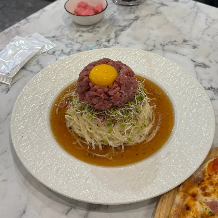 Perilla oil beef tartare cold pasta topped with an egg yolk