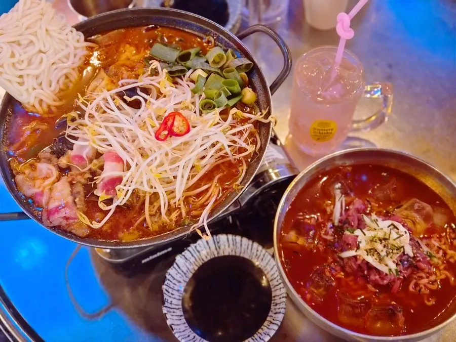 Table set with beef brisket jjamppong tang and yukhoe fire noodles served together