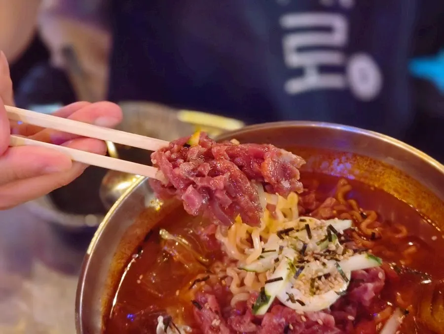 Noodles and yukhoe picked up together with chopsticks