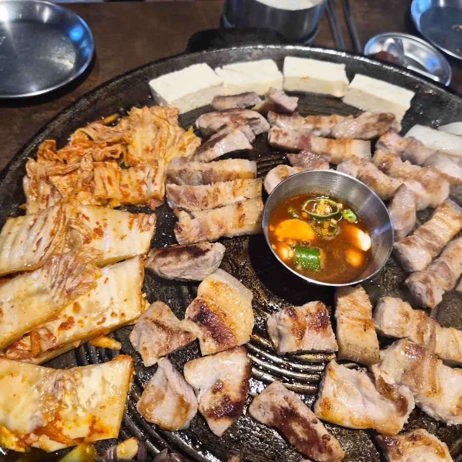 Ogyeopsal and stir-fried kimchi grilling on the cauldron lid