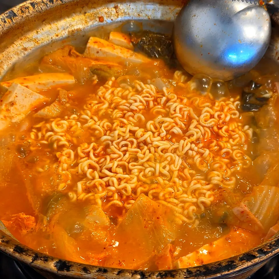 Pot of kimchi jjigae topped with ham
