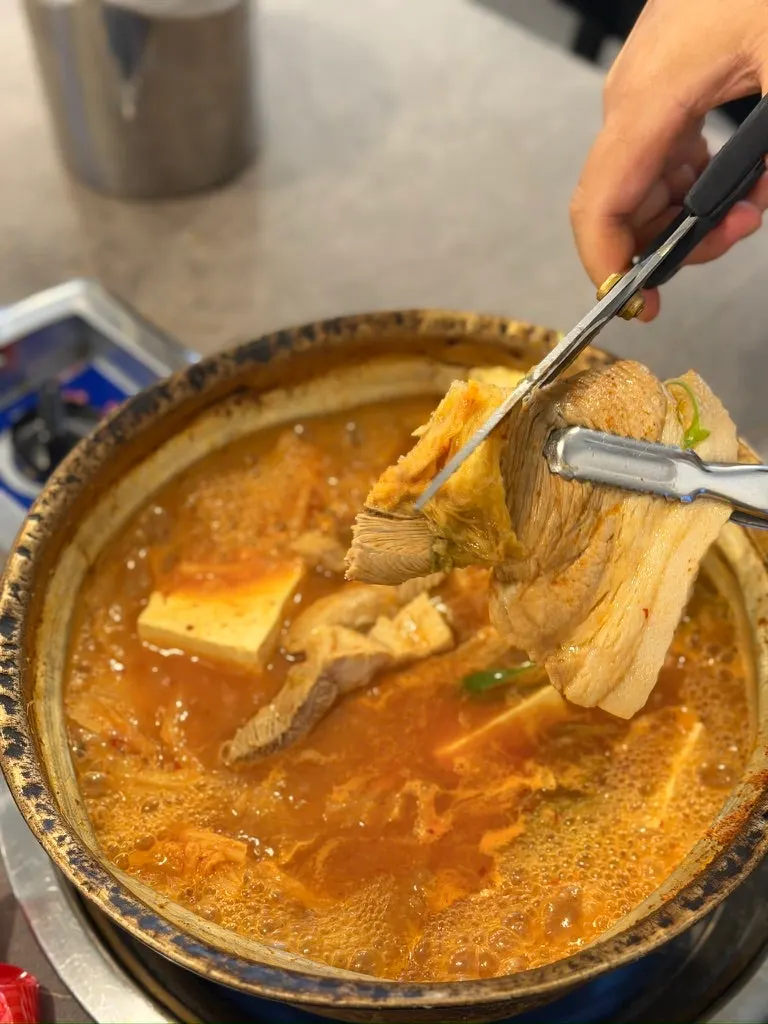 집게로 들어 올린 돼지고기 덩어리