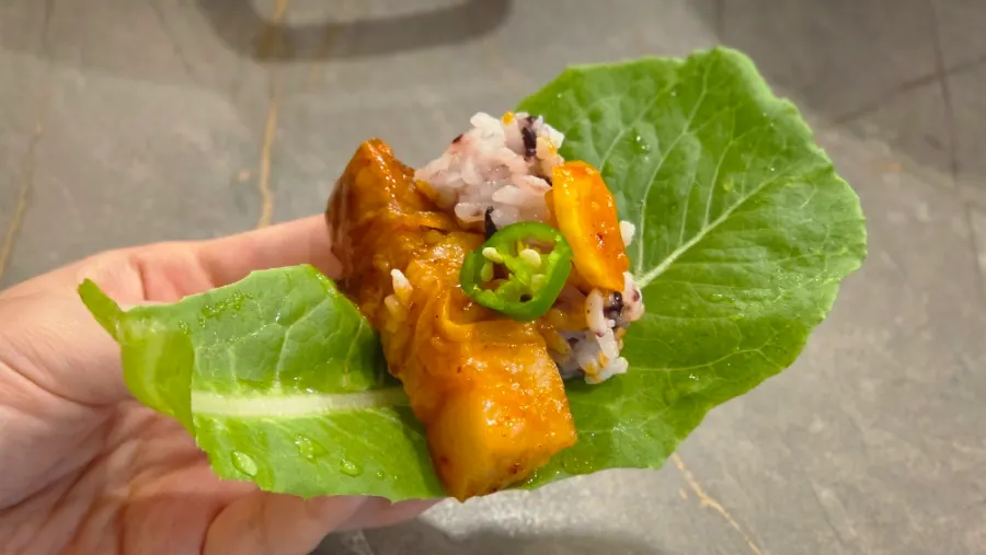 A wrap of lettuce and perilla leaf topped with seaweed flakes