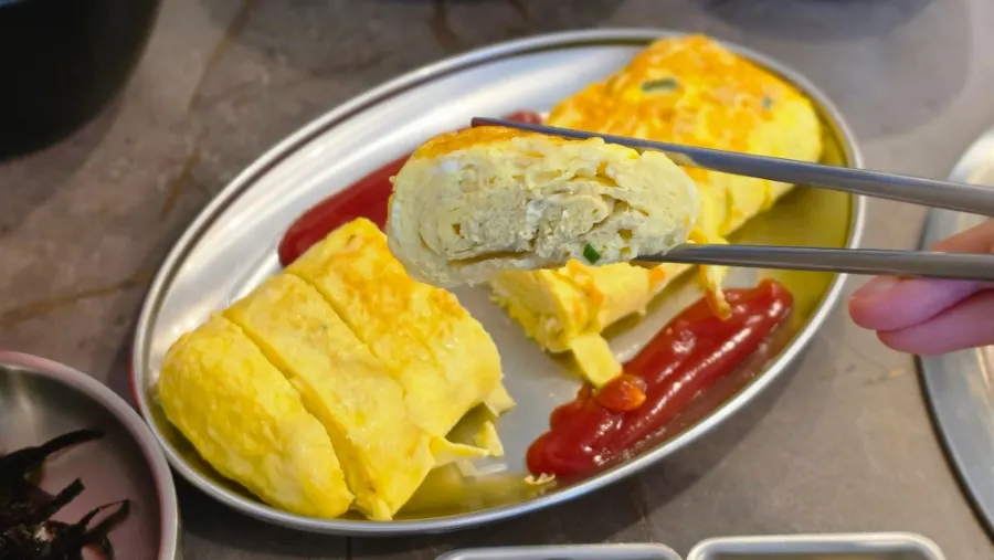 A piece of egg roll dipped in ketchup
