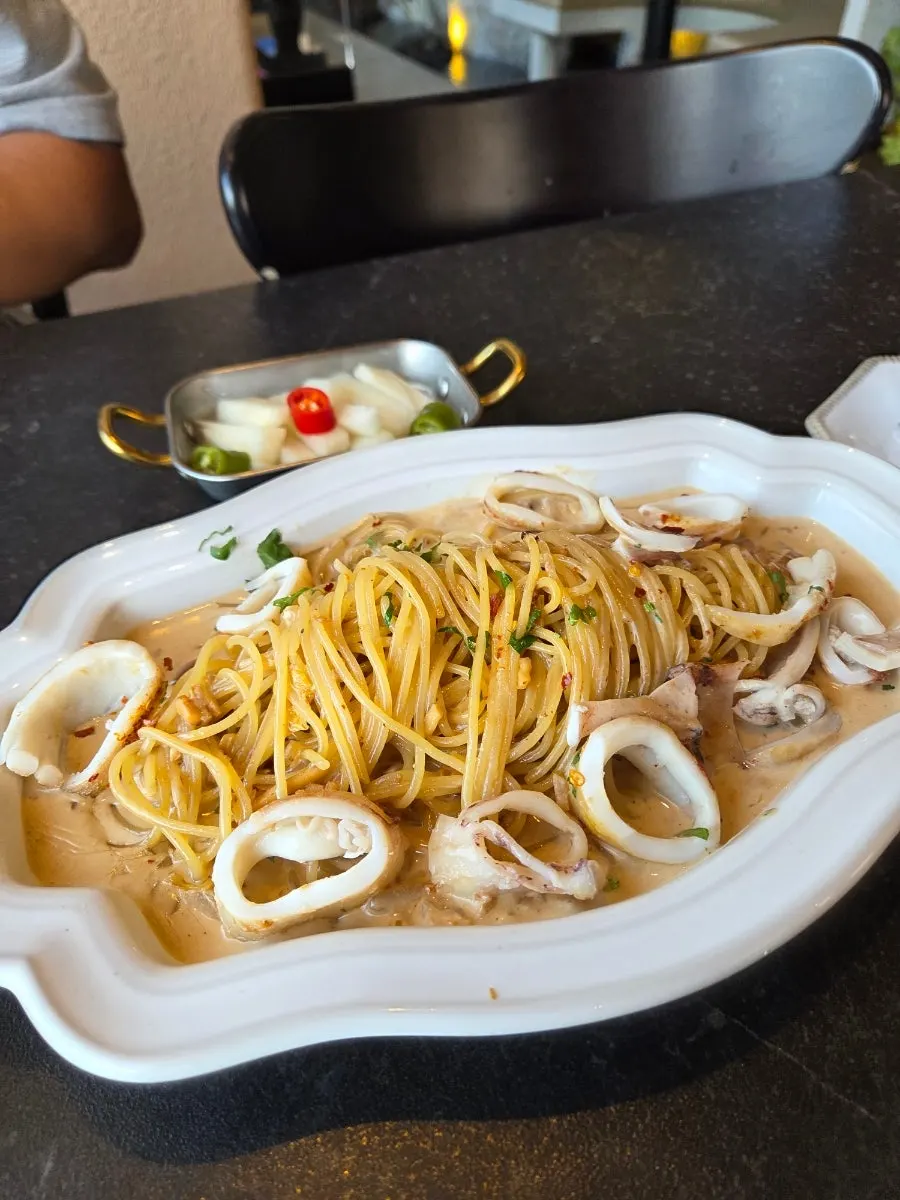 Cream pasta topped with a large squid