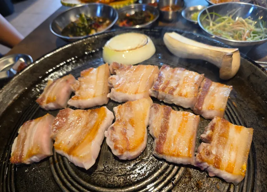 Pork belly grilling on the heated cauldron lid