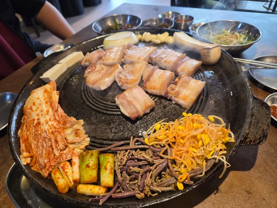 Staff member grilling meat on the cauldron lid