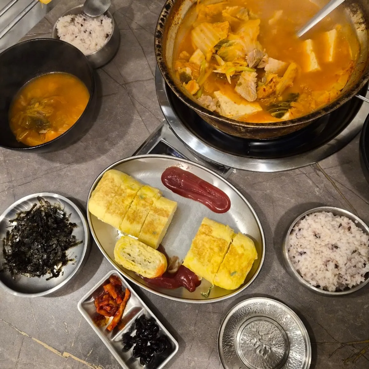 Kimchi jjigae set table spread with egg roll and rice