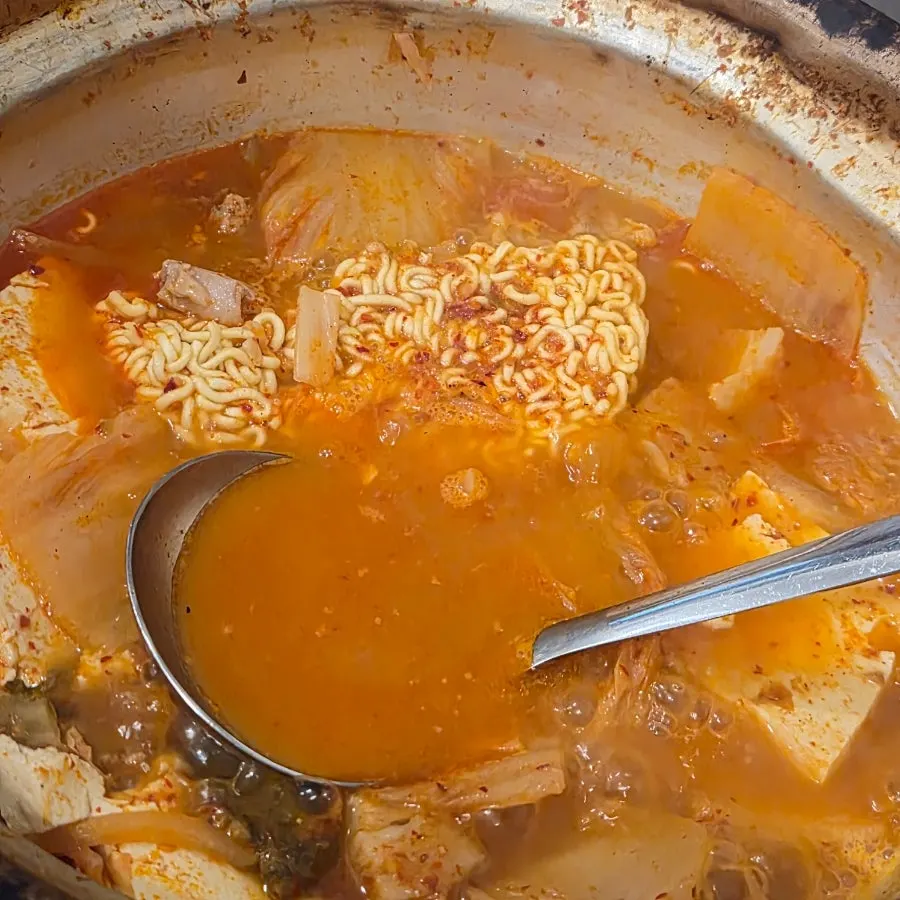 Ramyeon noodles being lifted out of the pot
