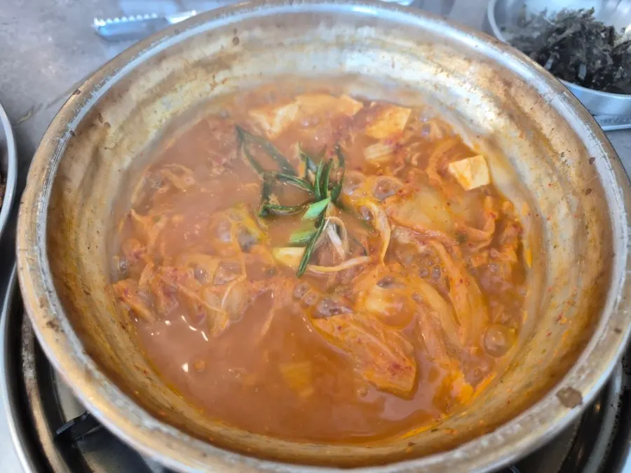 Single-serving kimchi jjigae served in a large metal bowl
