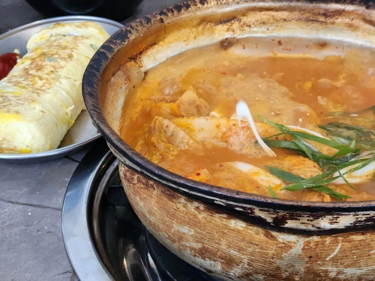 Kimchi jjigae bubbling in a metal pot