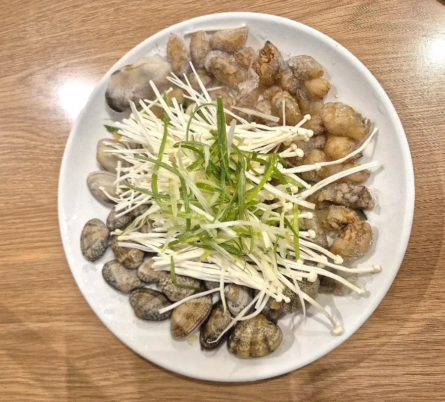 끓는 복해물칼국수와 테이블 위 모래시계