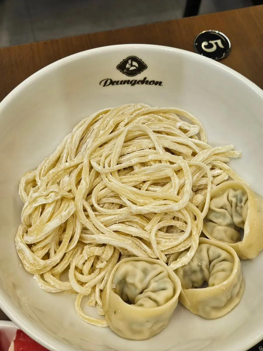 칼국수면과 만두 3알이 담긴 접시