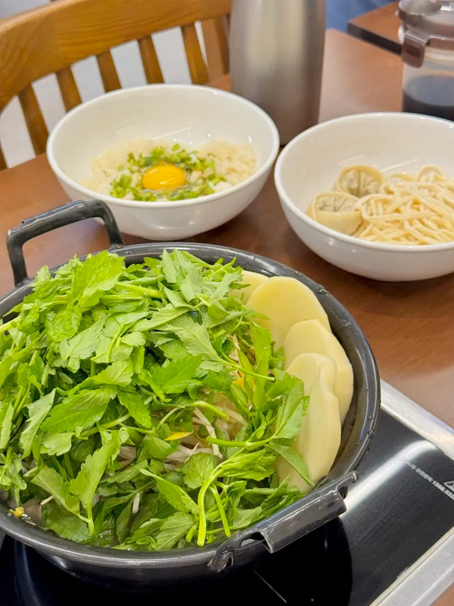 Pot piled high with water parsley, bean sprouts, and mushrooms