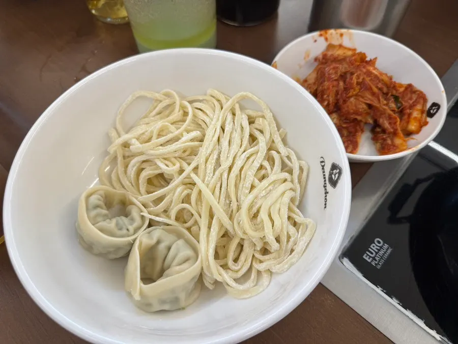 Boiling spicy mushroom kalguksu hot pot with dumplings and kimchi