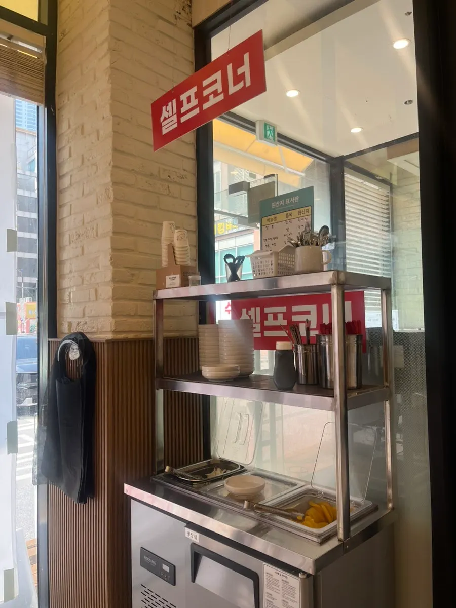 Self-serve corner with onions, pickled radish, and tableware