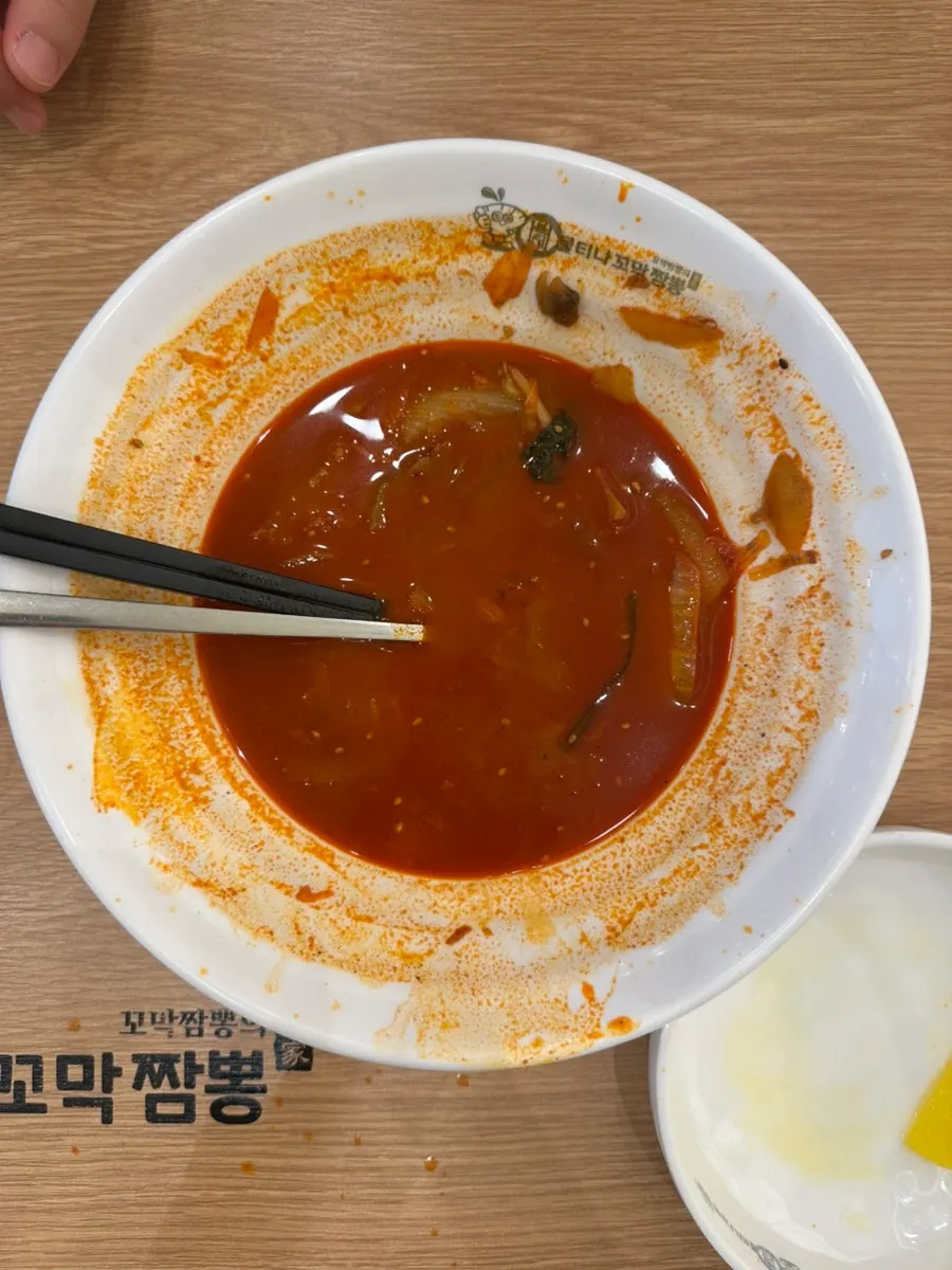 Close-up of the kkomak jjamppong broth, spoon lifted