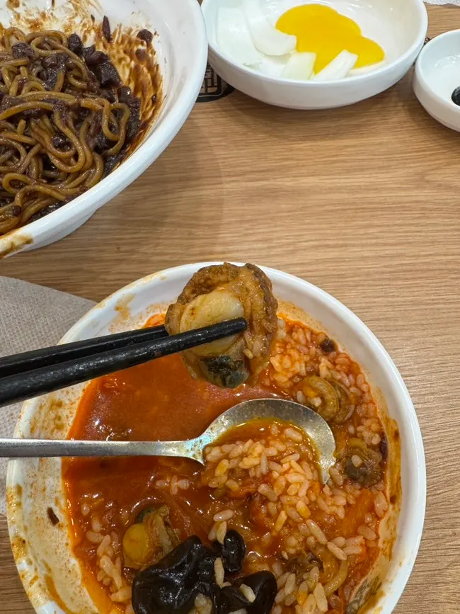 국물과 꼬막을 밥에 올린 한 숟갈
