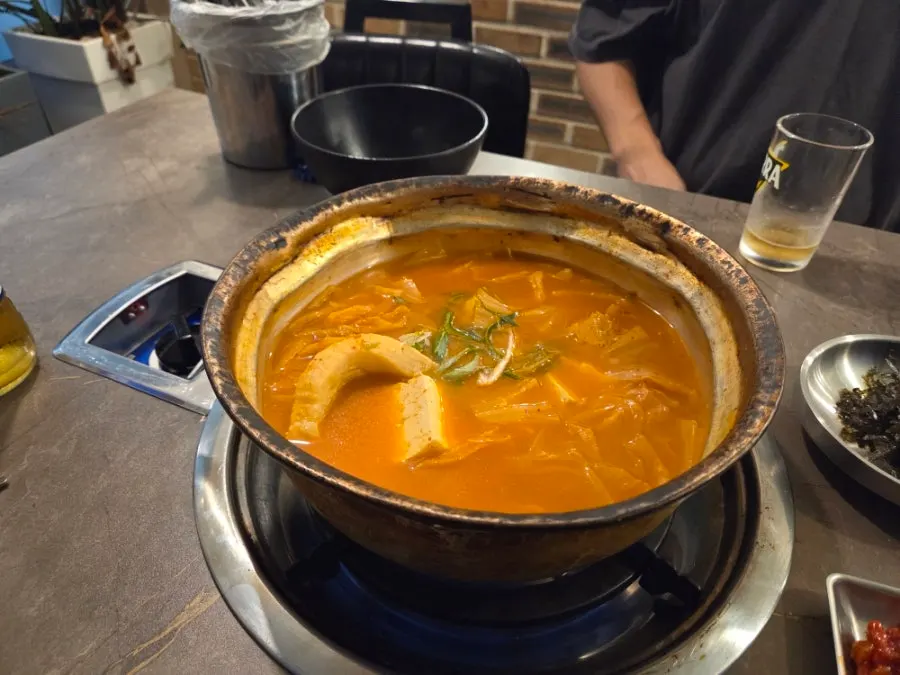 Kimchi jjigae served brimming in the yellow pot