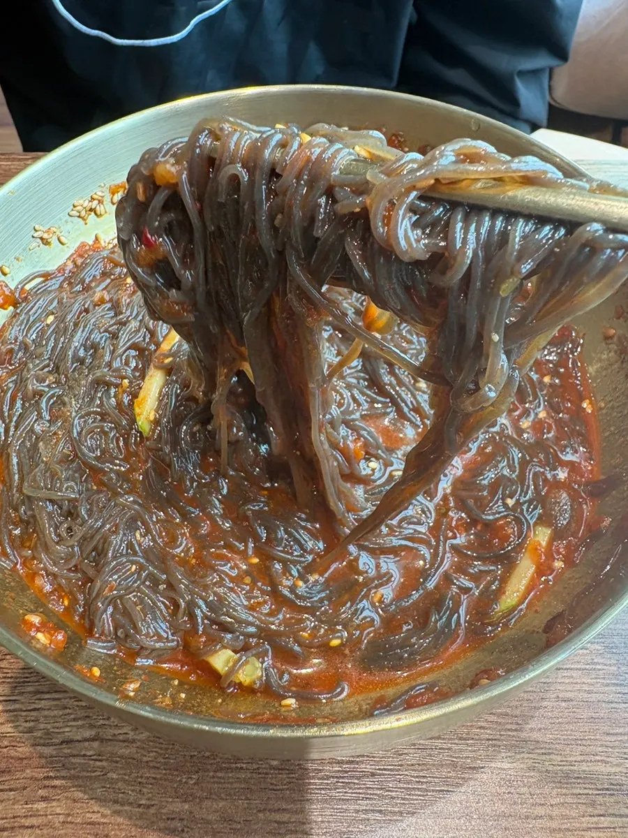 Bibim naengmyeon noodles lifted with chopsticks