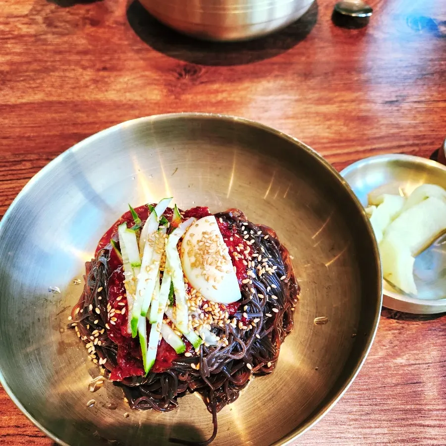 Table setting with mul naengmyeon, bibim naengmyeon, and dumplings