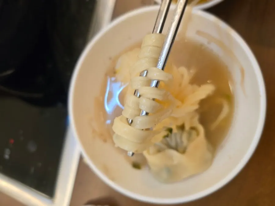 Scooping ingredients out of the mushroom shabu-shabu pot