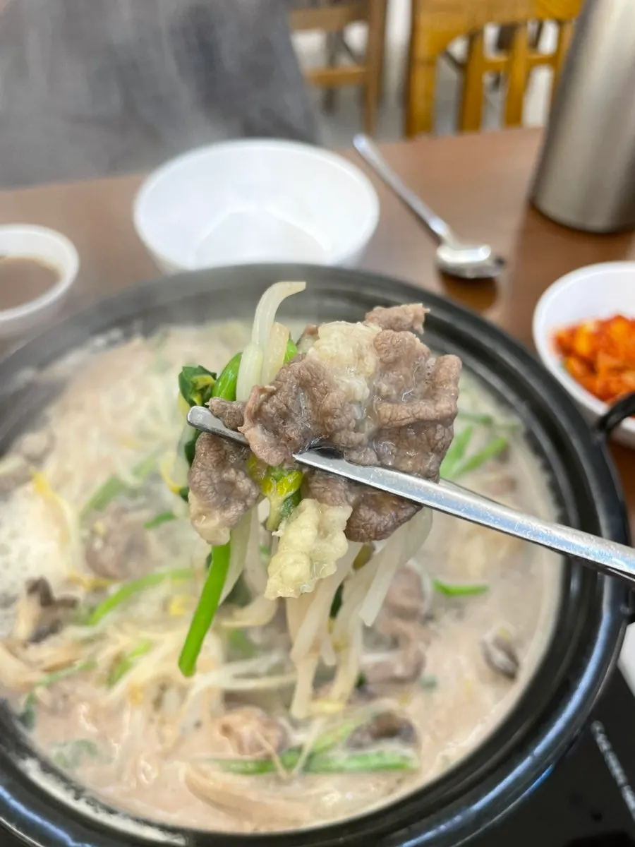 Cooked beef and vegetables scooped out of the pot