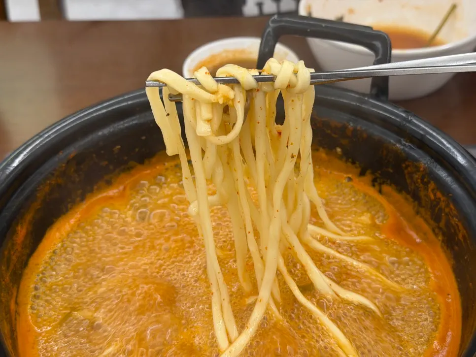 Kalguksu noodles added to the spicy broth