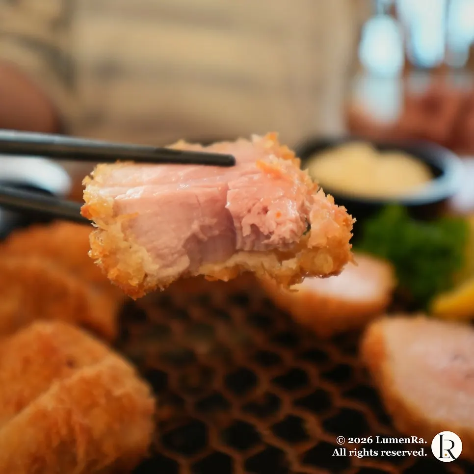 A piece of tenderloin kkot katsu picked up with chopsticks