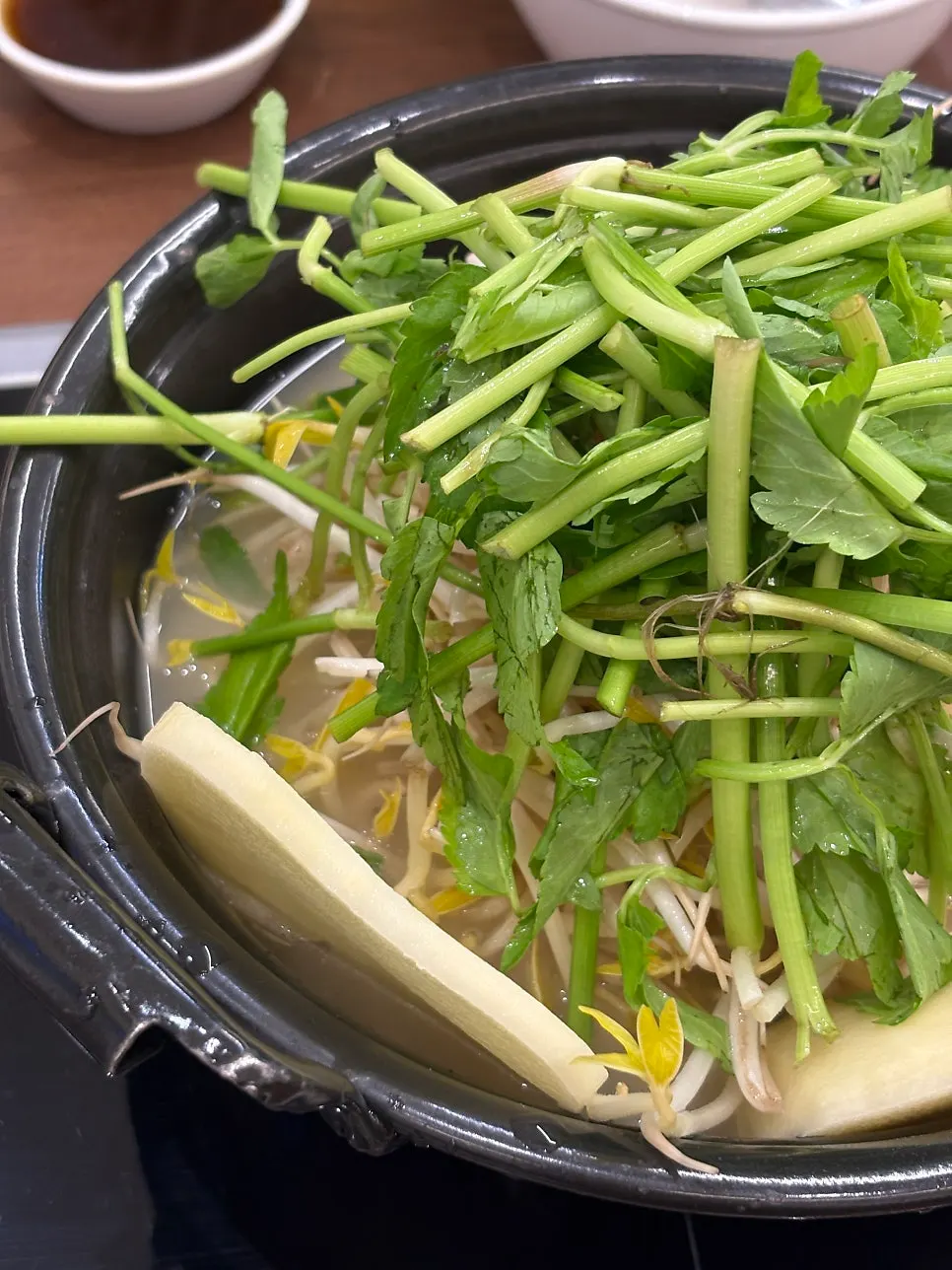 Clear broth hot pot piled high with minari