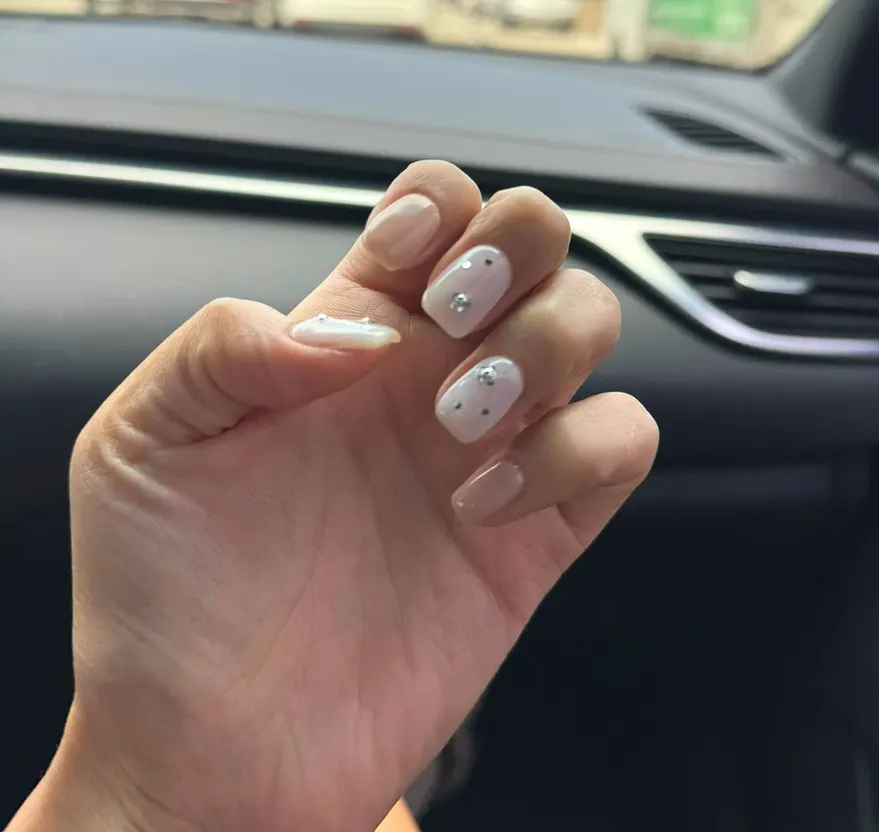 Finished gel nails in beige and white tones with cubic accents