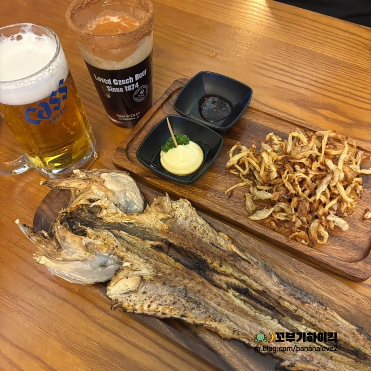 Kozel Dark draft topped with cinnamon powder next to a cream draft beer