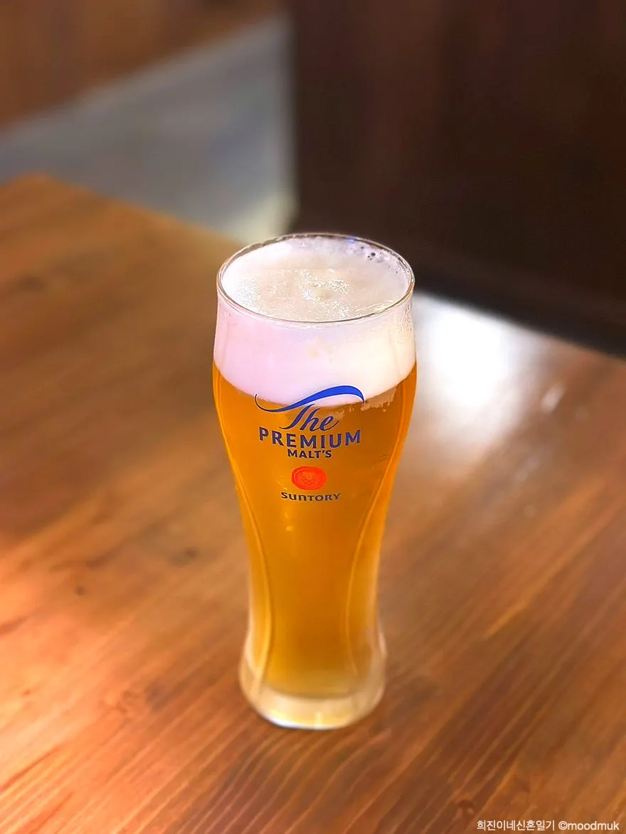 A glass of Suntory draft beer with foam on top