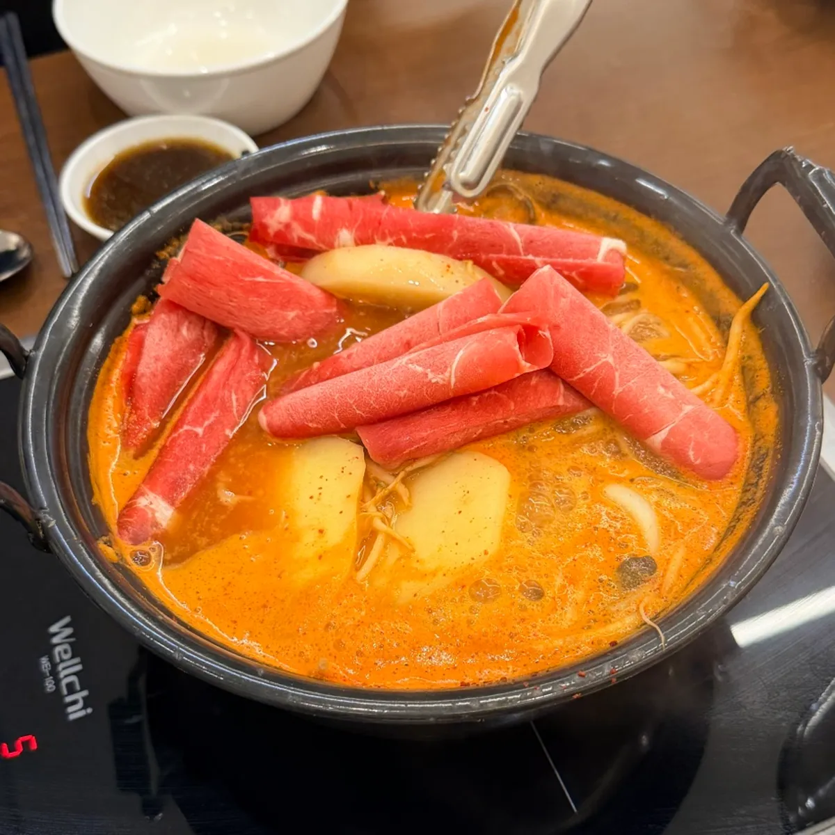 Adding shabu beef into the boiling spicy broth