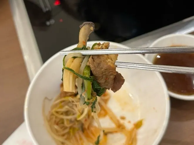 Dipping cooked beef and minari into sauce