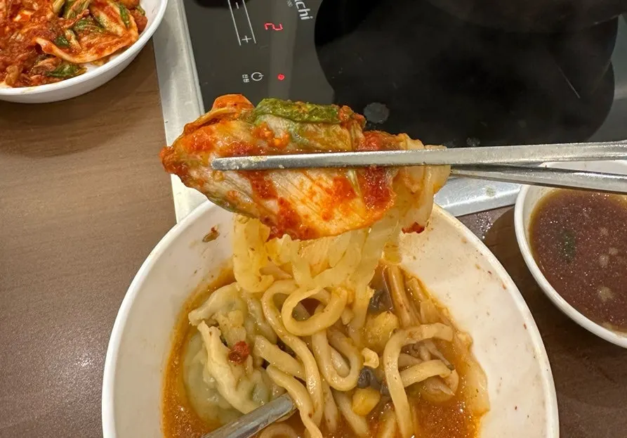Adding kalguksu noodles and dumplings to the pot