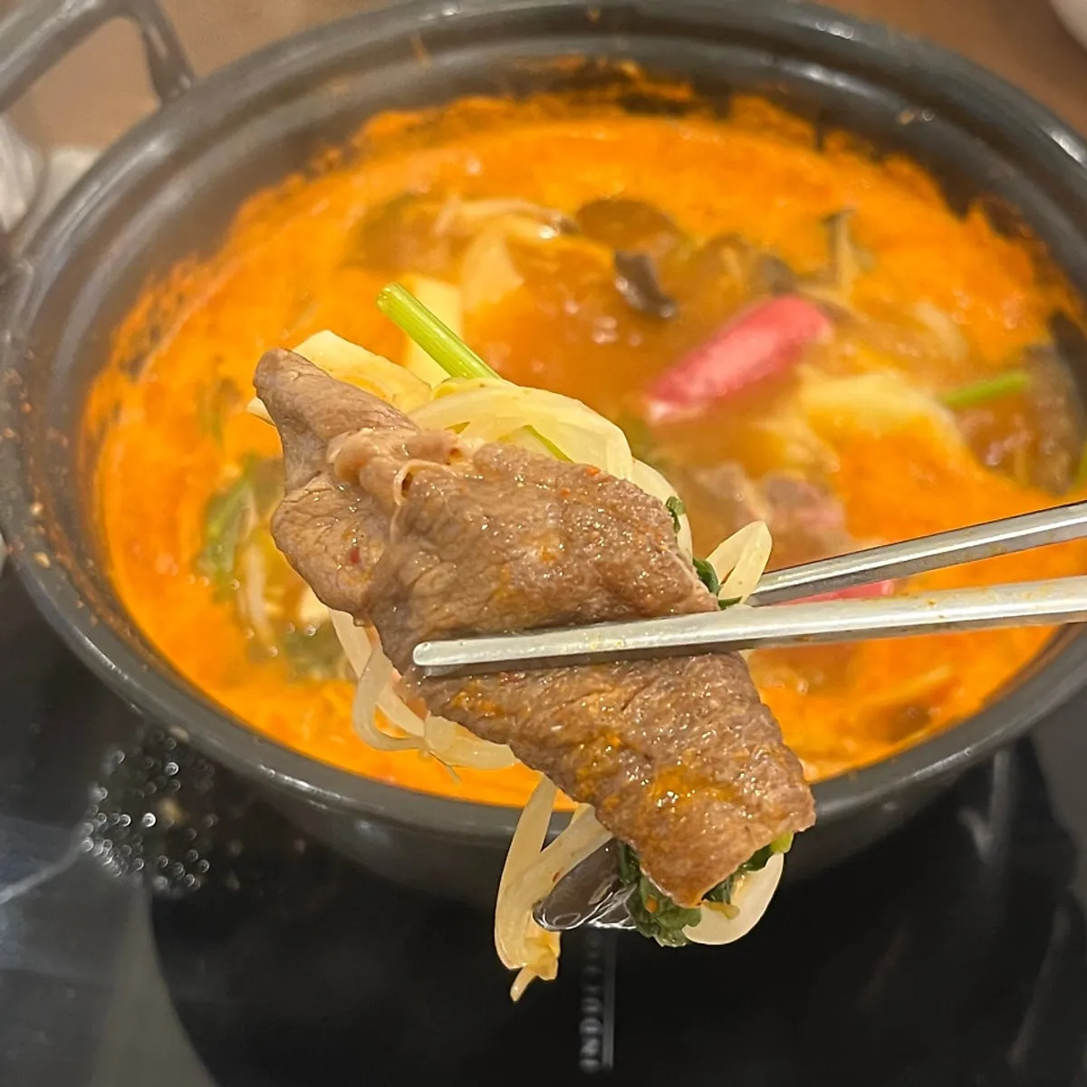 Pot full of blanched meat and vegetables in spicy broth