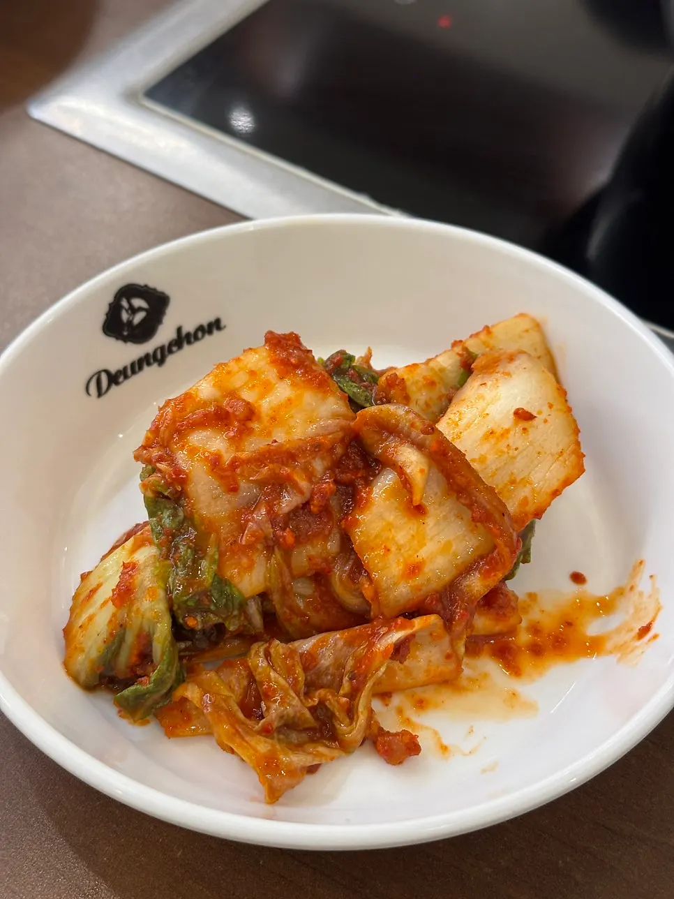 Pot of spicy broth topped with minari and bean sprouts