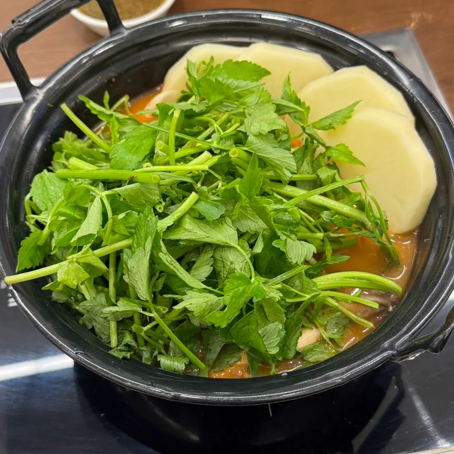 Shabu kalguksu pot piled high with minari
