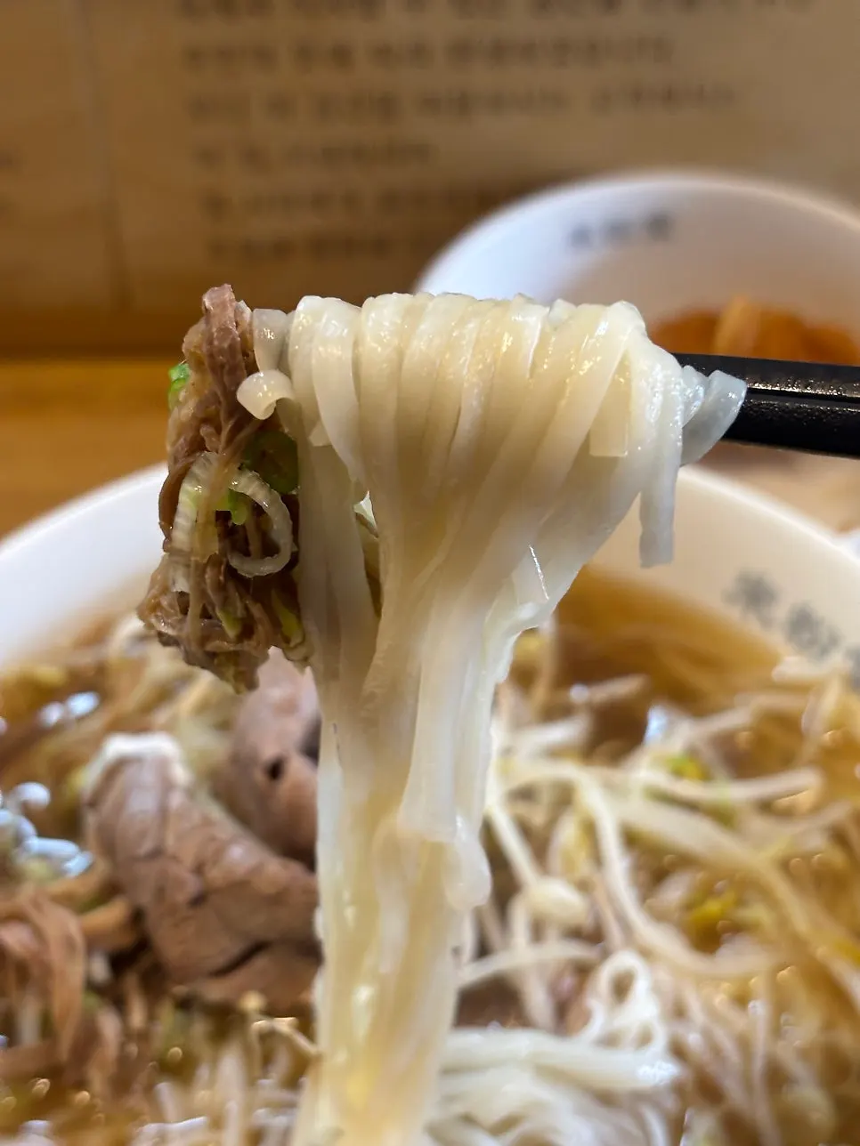 Pho noodles lifted with chopsticks