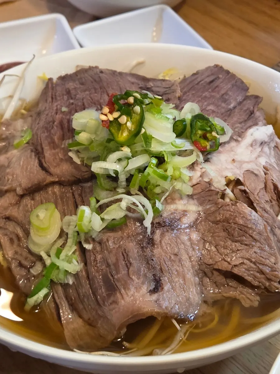 Pho topped with chopped scallions and chili