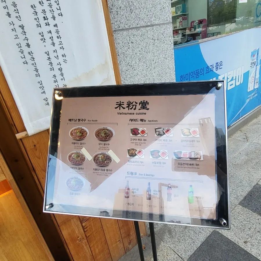 Menu board out front showing pho and side dishes