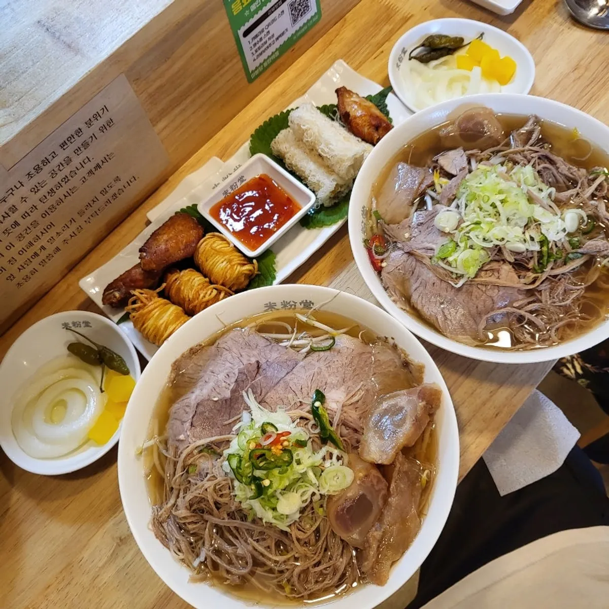 A generous bowl of pho with meat covering the noodles