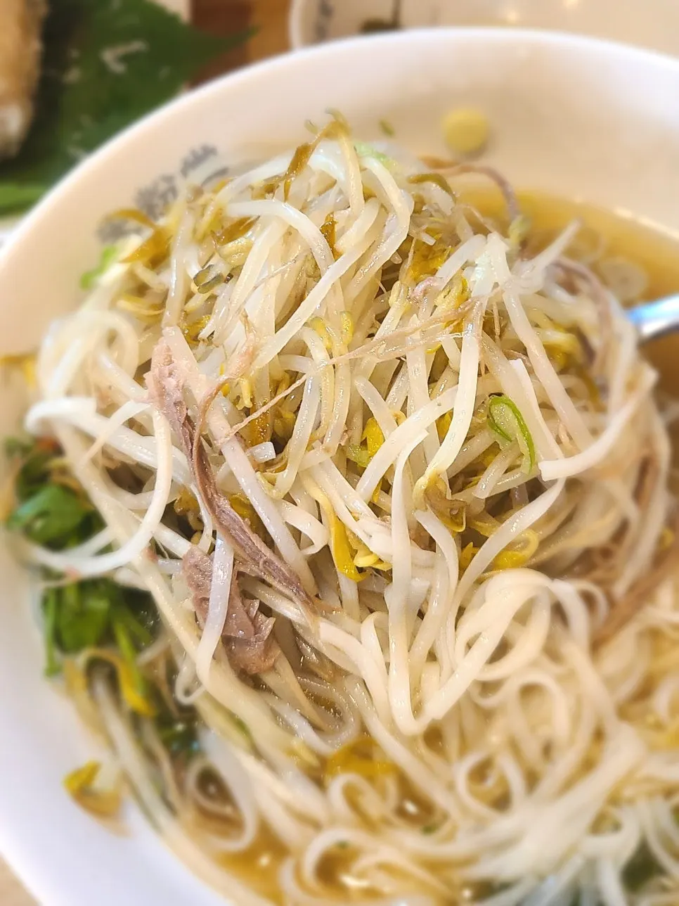 Chopsticks lifting pho noodles topped with cilantro