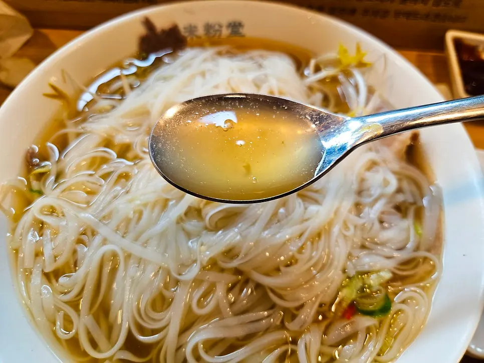 Clean pho broth with a piece of meat