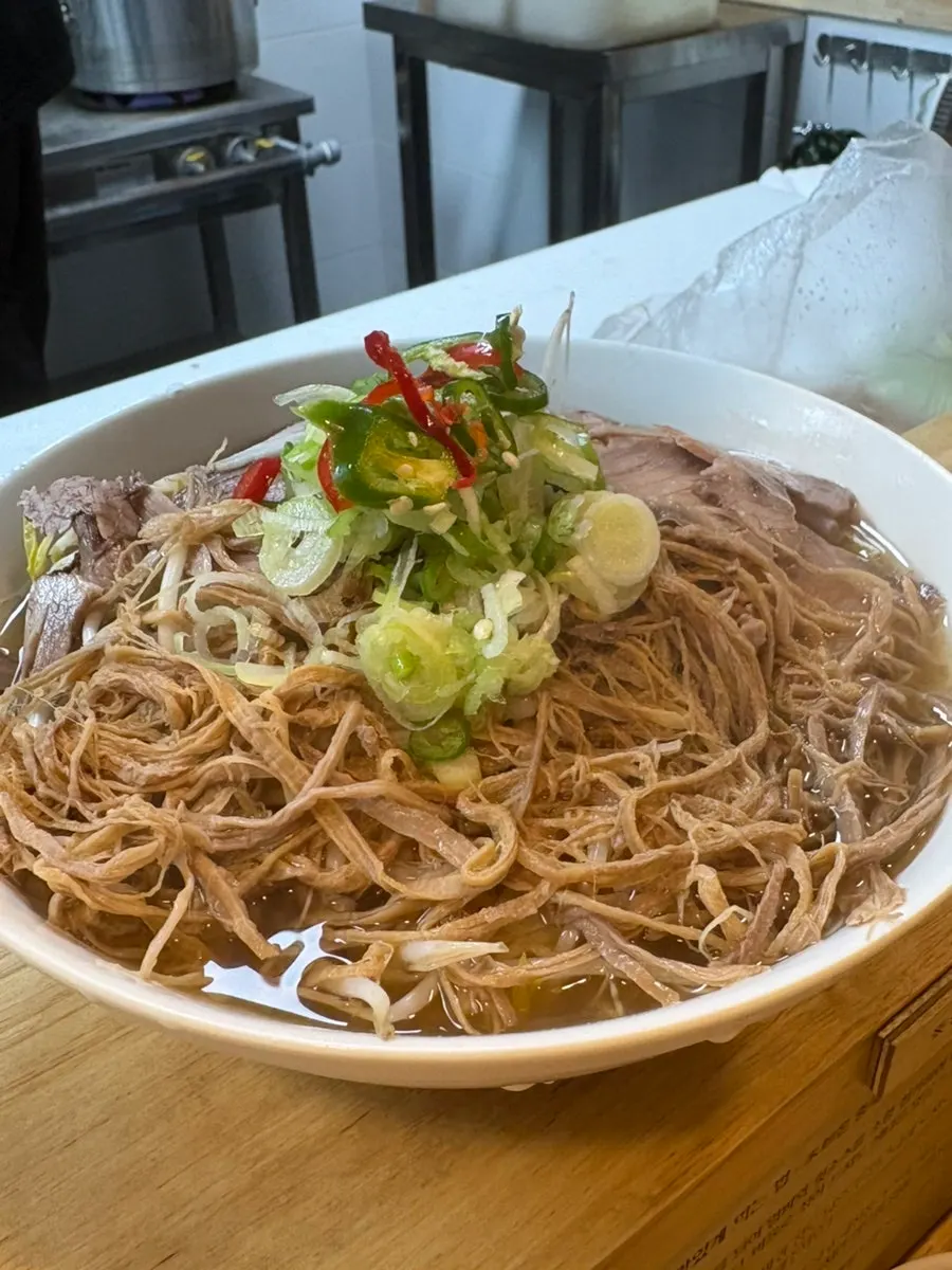 A bowl of pho topped with bean sprouts and meat