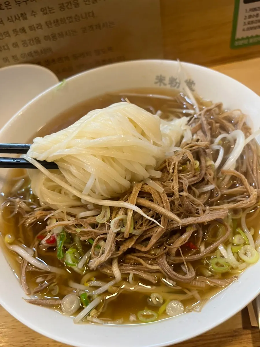 Chopsticks lifting noodles and bean sprouts together