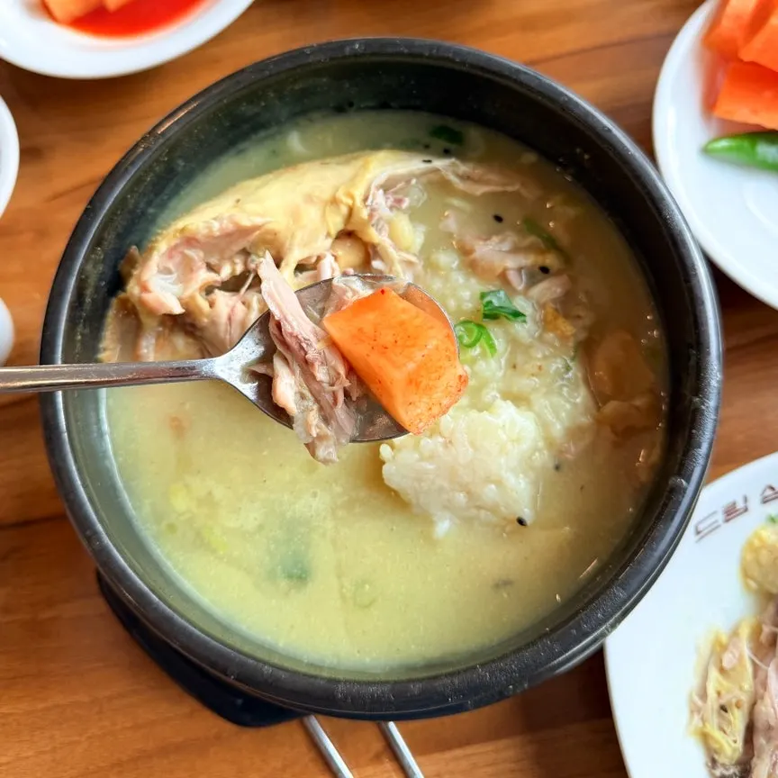 삼계탕 국물과 반찬이 놓인 테이블